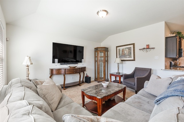 living room featuring lofted ceiling, light carpet, and baseboards