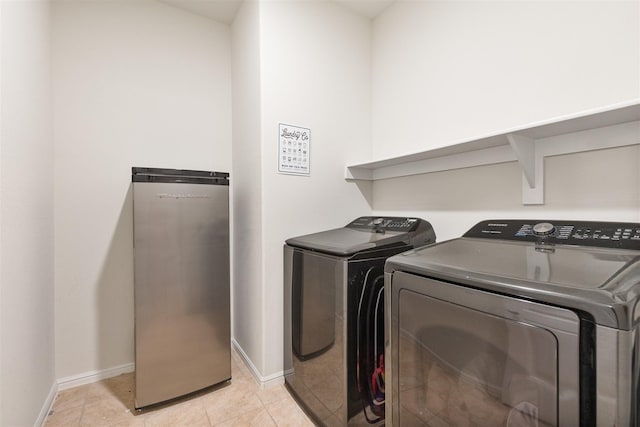 clothes washing area featuring laundry area, independent washer and dryer, baseboards, and light tile patterned floors