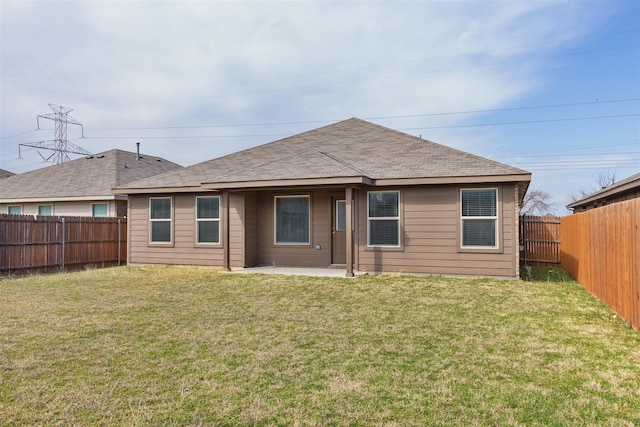 rear view of property featuring a shingled roof, a patio area, a fenced backyard, and a yard