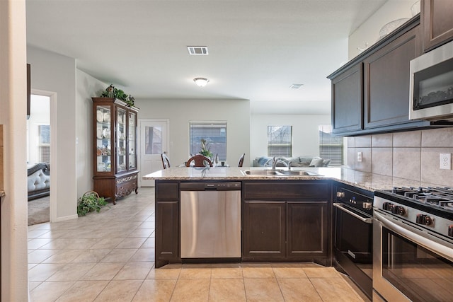 kitchen featuring a sink, visible vents, dark brown cabinets, appliances with stainless steel finishes, and backsplash