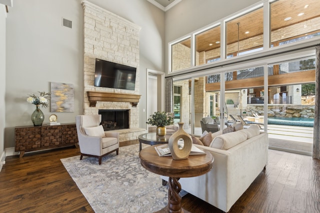 living area featuring wood-type flooring, a high ceiling, a fireplace, and crown molding