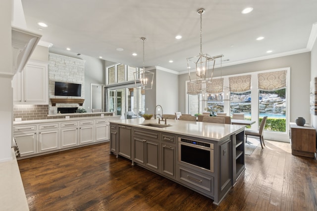 kitchen featuring light countertops, ornamental molding, white cabinets, stainless steel oven, and a sink