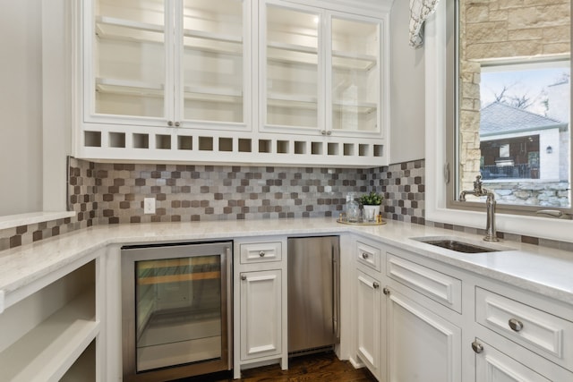 bar featuring tasteful backsplash, beverage cooler, stainless steel fridge, and a sink