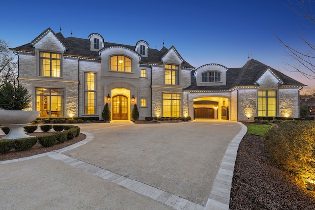 french country style house featuring stone siding, a high end roof, french doors, and driveway