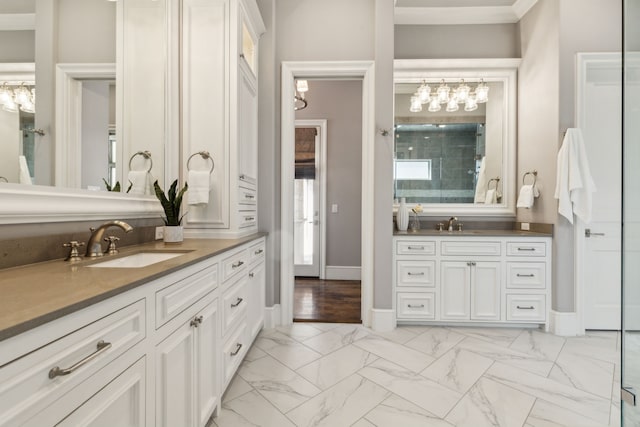 full bath with marble finish floor, two vanities, ornamental molding, a sink, and baseboards