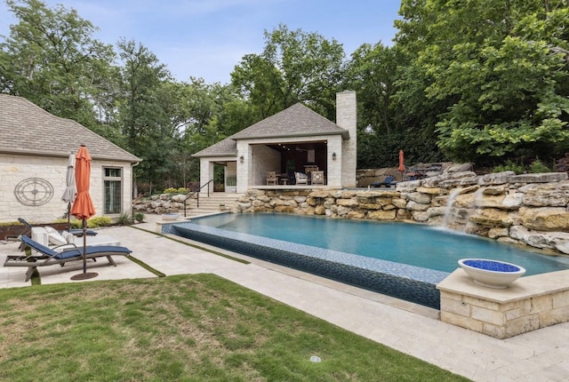 view of pool featuring an infinity pool, an outdoor structure, a patio, and an exterior structure