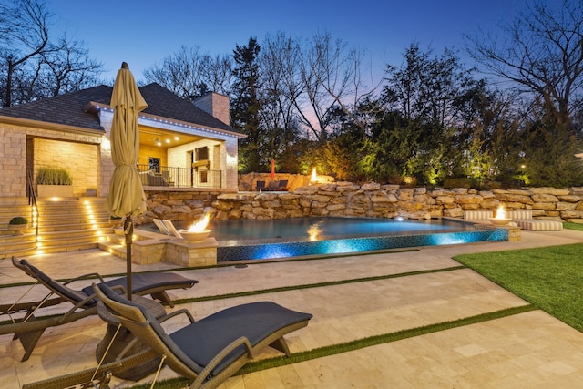 outdoor pool featuring an outdoor fire pit and a patio area