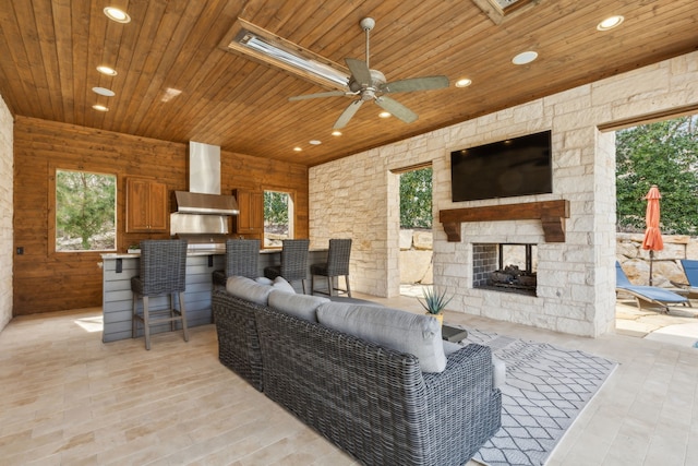 living room featuring a wealth of natural light, wood ceiling, an outdoor stone fireplace, and recessed lighting