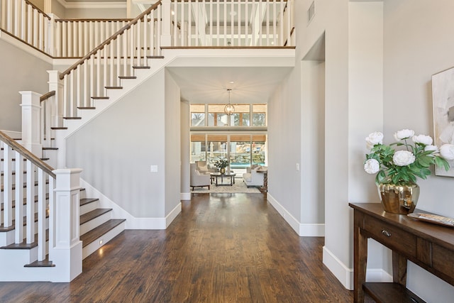 foyer entrance with wood finished floors, visible vents, a towering ceiling, stairs, and baseboards