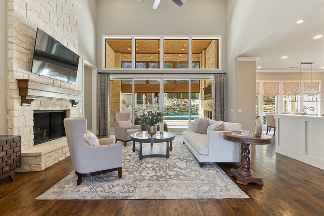 living room with ceiling fan, recessed lighting, a high ceiling, a fireplace, and wood finished floors