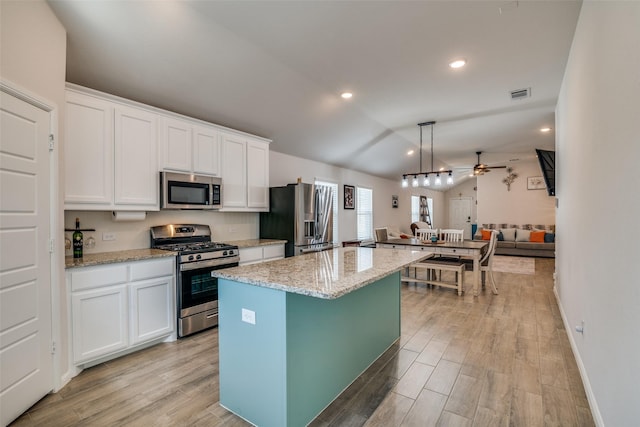 kitchen featuring visible vents, white cabinets, lofted ceiling, a center island, and stainless steel appliances