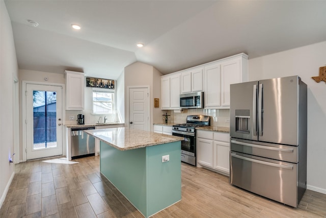 kitchen with white cabinets, tasteful backsplash, vaulted ceiling, and stainless steel appliances