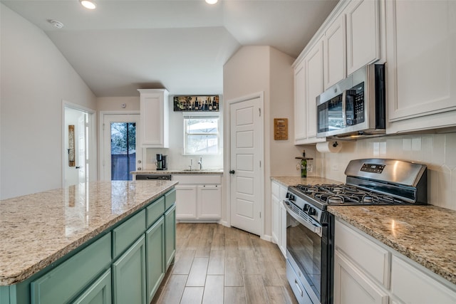 kitchen with stainless steel appliances, vaulted ceiling, a sink, and green cabinets