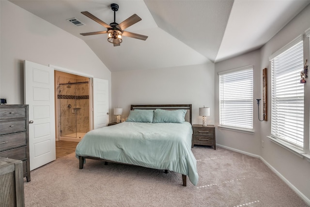 bedroom featuring baseboards, visible vents, light colored carpet, lofted ceiling, and ensuite bath