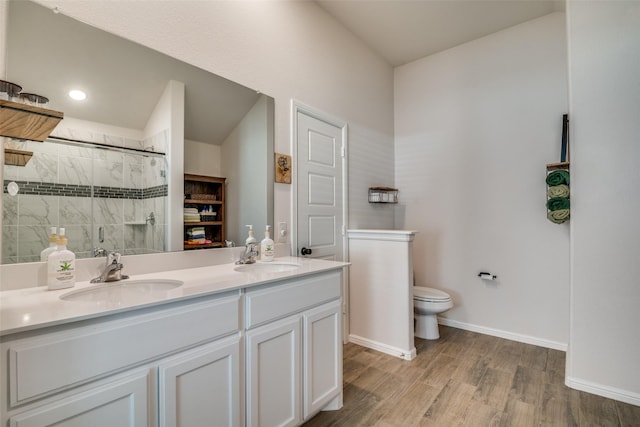 bathroom featuring wood finished floors, a sink, toilet, and a shower stall