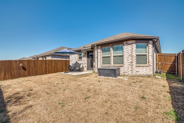 rear view of house with a patio area, brick siding, a lawn, and a fenced backyard