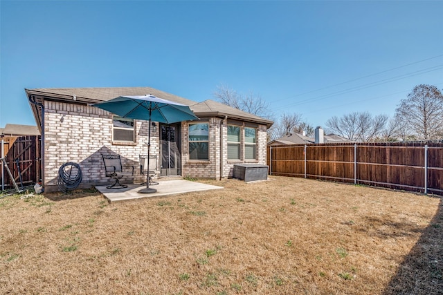 back of property with brick siding, a lawn, a patio area, and a fenced backyard