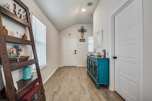 entrance foyer featuring light wood-style floors, visible vents, vaulted ceiling, and baseboards