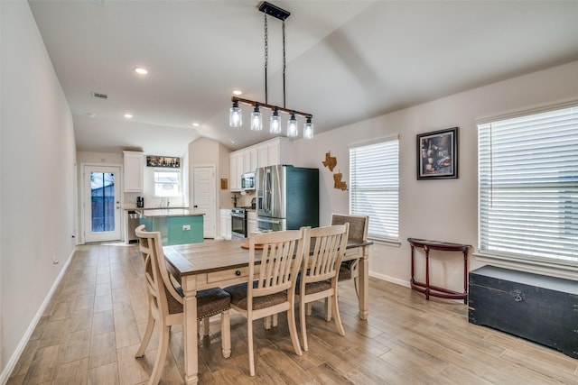 dining area featuring lofted ceiling, baseboards, visible vents, and light wood finished floors