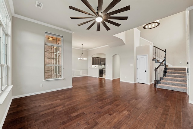 unfurnished living room with visible vents, stairway, an inviting chandelier, ornamental molding, and wood finished floors