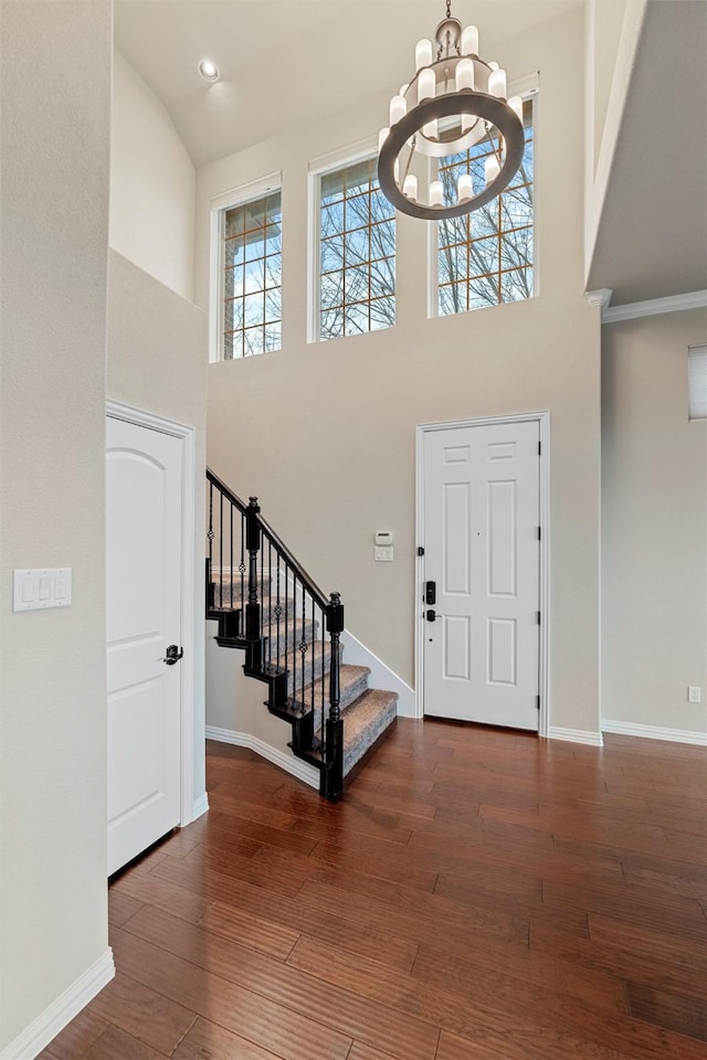 foyer with a chandelier, stairway, baseboards, and wood finished floors