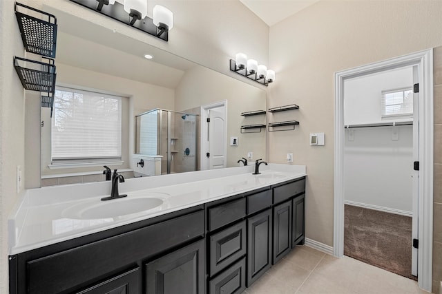 full bathroom featuring double vanity, a stall shower, tile patterned flooring, and a sink