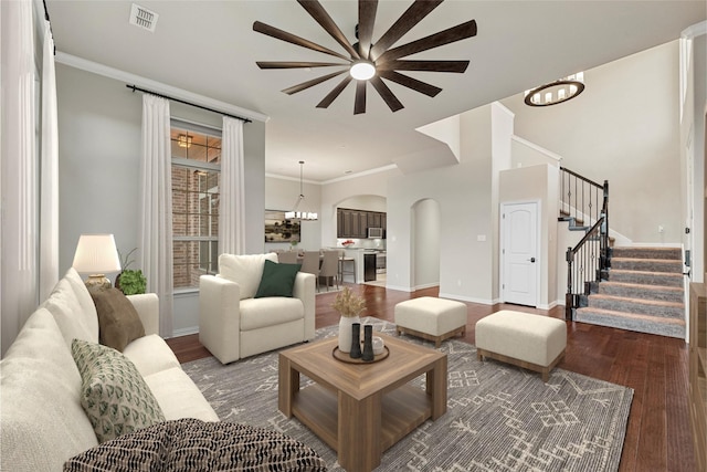 living area with visible vents, a notable chandelier, stairway, and wood finished floors