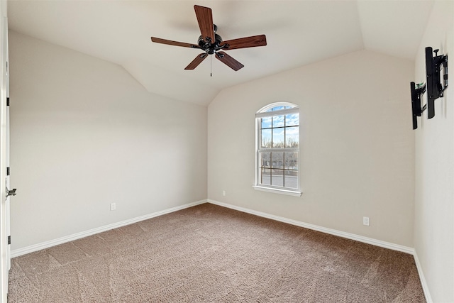 empty room with a ceiling fan, lofted ceiling, carpet flooring, and baseboards