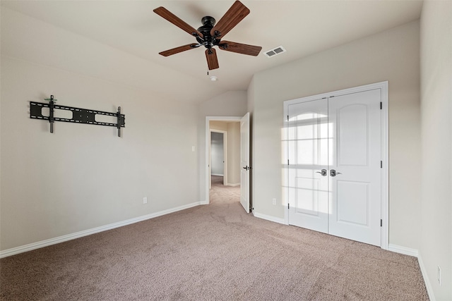 unfurnished bedroom featuring carpet, visible vents, vaulted ceiling, and baseboards