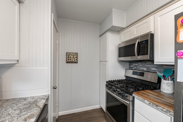 kitchen with tasteful backsplash, appliances with stainless steel finishes, white cabinets, and dark wood-type flooring