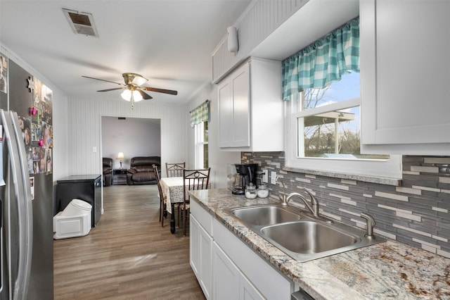 kitchen with wood finished floors, a sink, visible vents, light countertops, and freestanding refrigerator