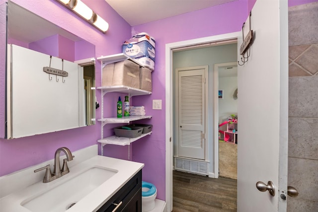 bathroom with toilet, wood finished floors, and vanity