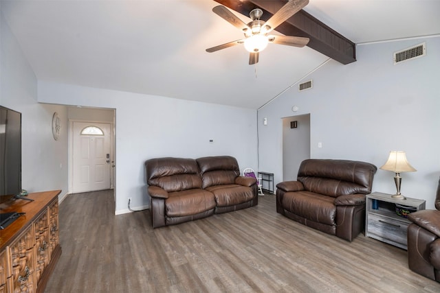 living room featuring visible vents, vaulted ceiling with beams, baseboards, and wood finished floors