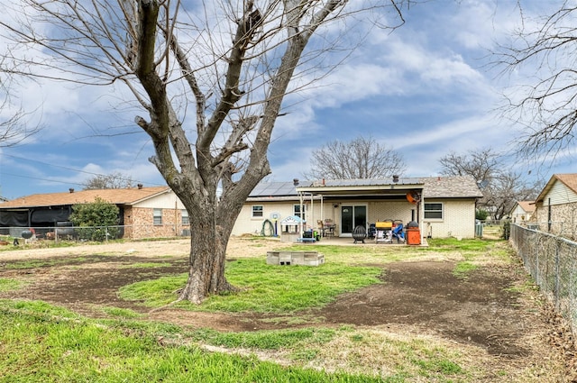 back of property featuring brick siding, a fenced backyard, solar panels, and a patio