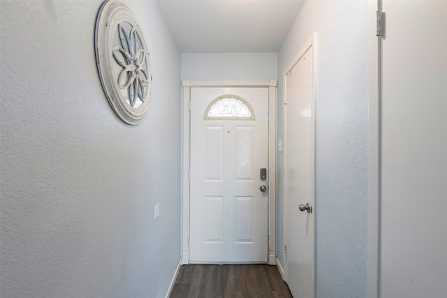 doorway to outside featuring a textured wall and dark wood finished floors