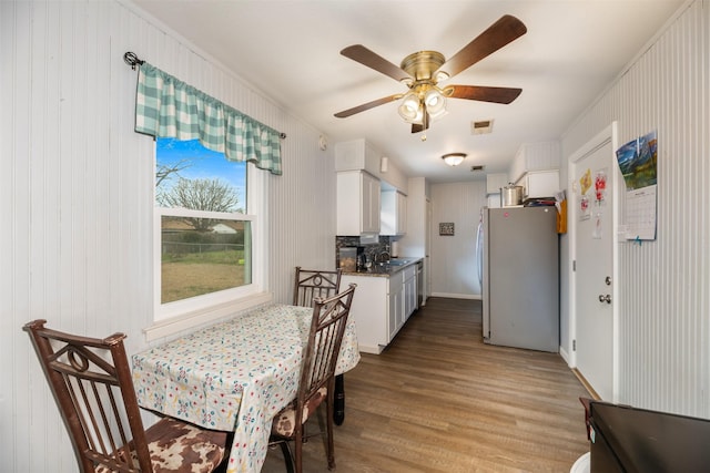 dining space with ceiling fan, visible vents, and wood finished floors