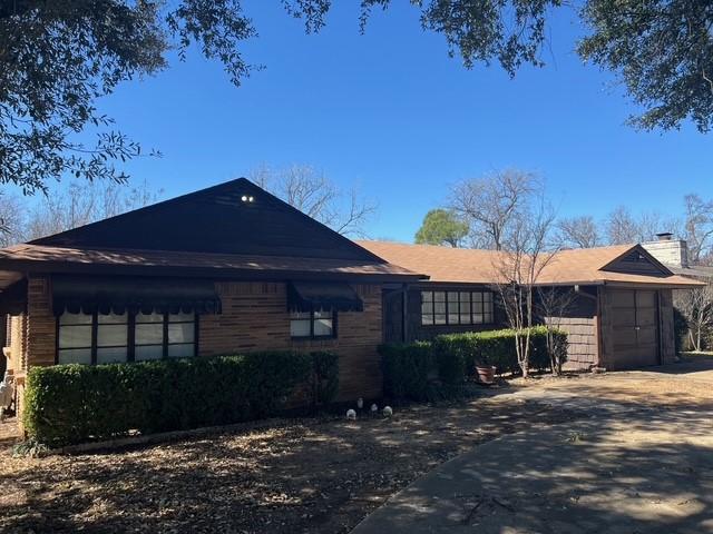 ranch-style home with driveway, a chimney, and an attached garage