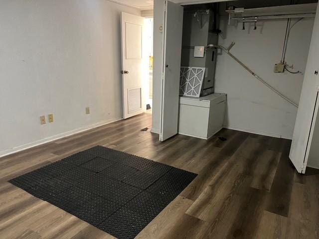 basement featuring heating unit, baseboards, and dark wood-style flooring