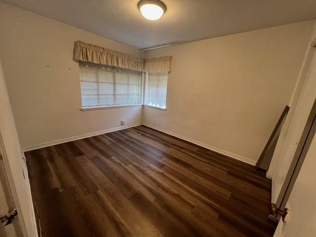 unfurnished room with dark wood finished floors and baseboards