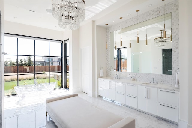 bathroom featuring a sink, marble finish floor, a notable chandelier, and backsplash