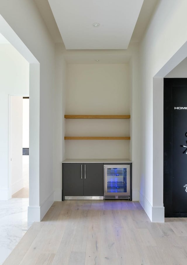 bar featuring wine cooler, baseboards, and wood finished floors