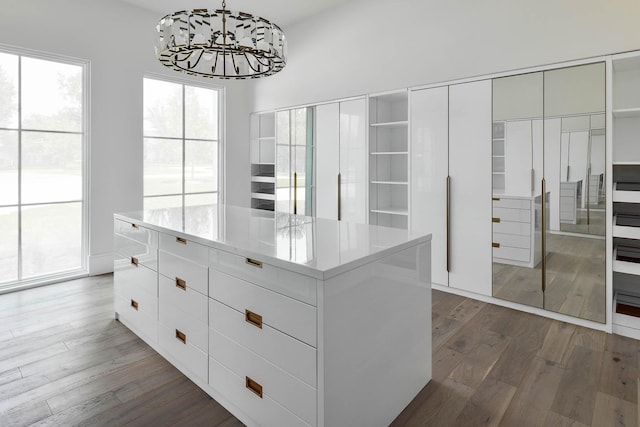 spacious closet featuring an inviting chandelier and hardwood / wood-style flooring