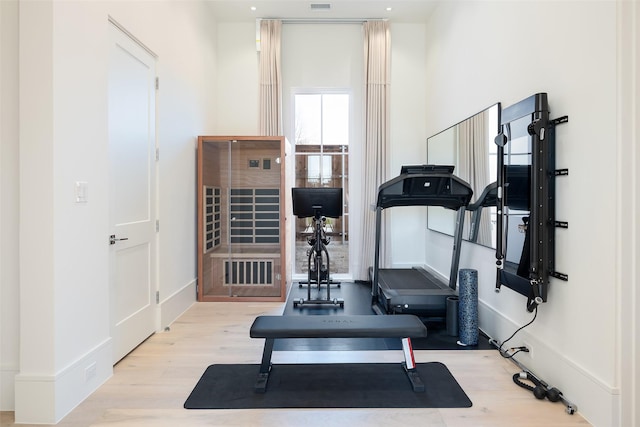 workout area with wood finished floors, visible vents, and baseboards