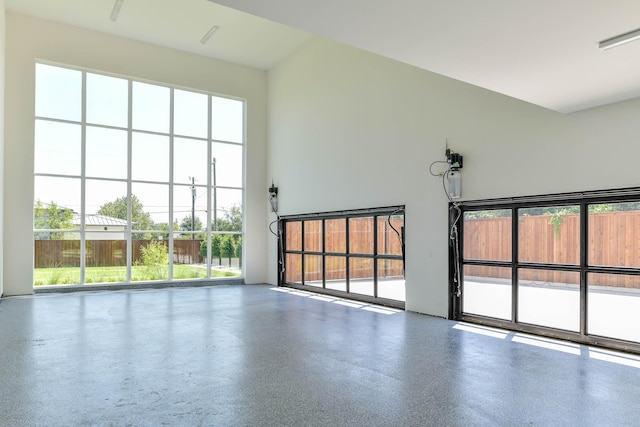 empty room featuring speckled floor and a towering ceiling