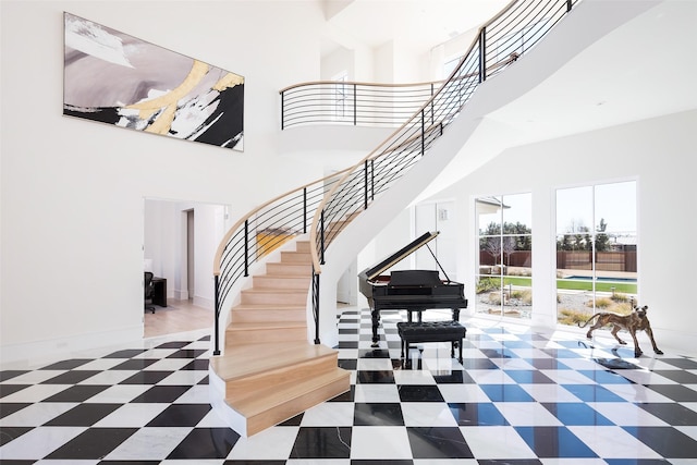 stairway featuring a towering ceiling, baseboards, and tile patterned floors