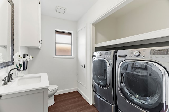 laundry room featuring dark wood-type flooring, washing machine and dryer, a sink, and baseboards