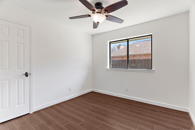 spare room featuring a ceiling fan, baseboards, and dark wood-style flooring