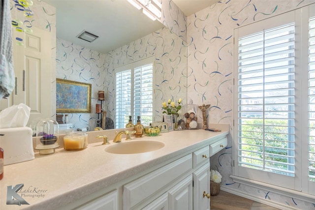 bathroom featuring visible vents, vanity, and wallpapered walls