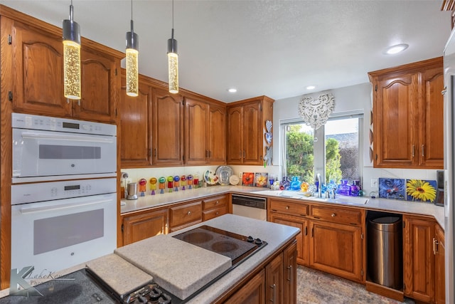 kitchen featuring dishwasher, white double oven, a sink, and brown cabinets