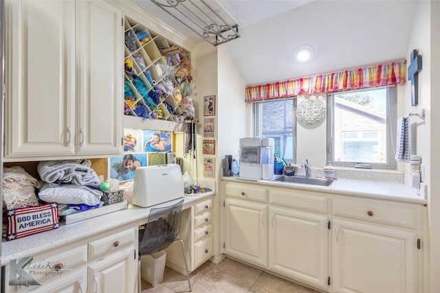 kitchen featuring light tile patterned floors, light countertops, a sink, and built in study area